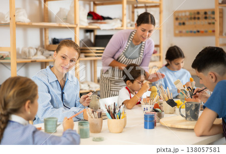 Children painting ceramics with a teacher 138057581