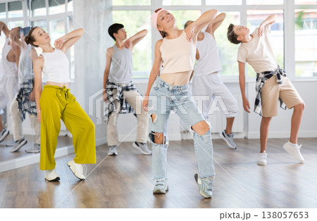 Active teenagers practicing hip hop dance in training hall during group dancing classes 138057653