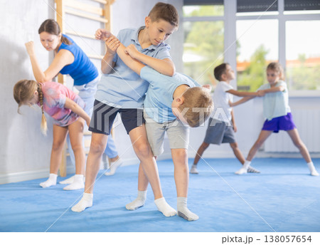 Children, boy and girl, working in pair mastering new self-defense moves at gym Children, boy and girl, working in pair mastering new self-defense moves at gym 138057654