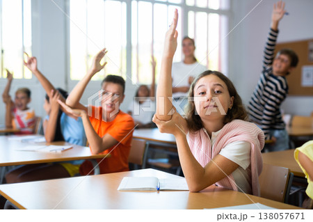 Girl raising her hand during lesson in school Girl raising her hand during lesson in school 138057671