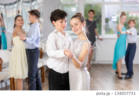 Positive teen boy and girl are dancing classic version of waltz in couple during lesson at studio Positive teen boy and girl are dancing classic version of waltz in couple during lesson at studio 138057733