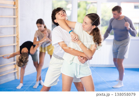 Boy and girl train to perform works out blow to jaw at opponent, while learning self-defense Boy and girl train to perform works out blow to jaw at opponent, while learning self-defense 138058079