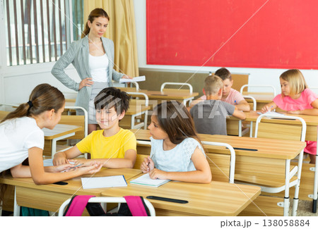 Preteen schoolchilds working in groups at lesson 138058884