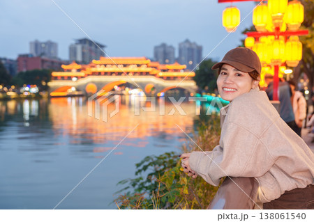 Happy woman traveler travel in Chengdu city. Tourist sightseeing Beautiful Anshun Bridge at night. Famous Landmark for tourism attraction in Sichuan, China 138061540