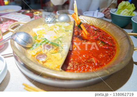 Woman tourist eating traditional hot pot or mala spicy soup in restaurant. Popular foods for tourist eating in Chengdu, Chongqing and China. Chinese Asia and Sichuan foods concept Woman tourist eating traditional hot pot or mala spicy soup in restaurant. Popular foods for tourist eating in Chengdu, Chongqing and China. Chinese Asia and Sichuan foods concept 138062719