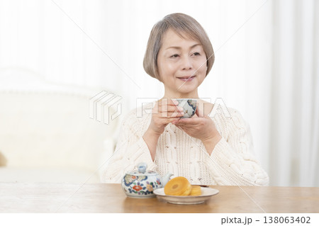 リビングでおやつを食べながらお茶を飲むシニア女性 138063402