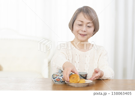 リビングでおやつを食べながらお茶を飲むシニア女性 138063405