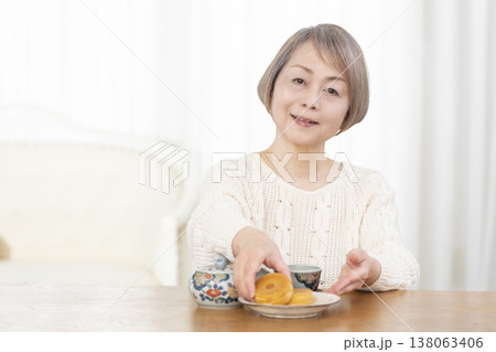 リビングでおやつを食べながらお茶を飲むシニア女性 リビングでおやつを食べながらお茶を飲むシニア女性 138063406