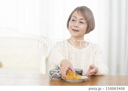 リビングでおやつを食べながらお茶を飲むシニア女性 リビングでおやつを食べながらお茶を飲むシニア女性 138063408