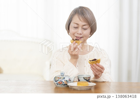 リビングでおやつを食べながらお茶を飲むシニア女性 リビングでおやつを食べながらお茶を飲むシニア女性 138063418