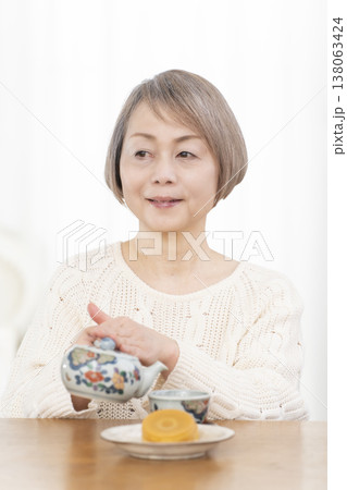 リビングでおやつを食べながらお茶を飲むシニア女性 リビングでおやつを食べながらお茶を飲むシニア女性 138063424