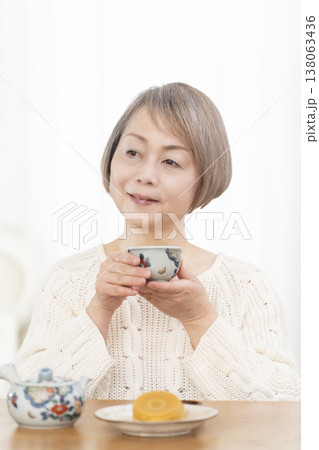 リビングでおやつを食べながらお茶を飲むシニア女性 138063436