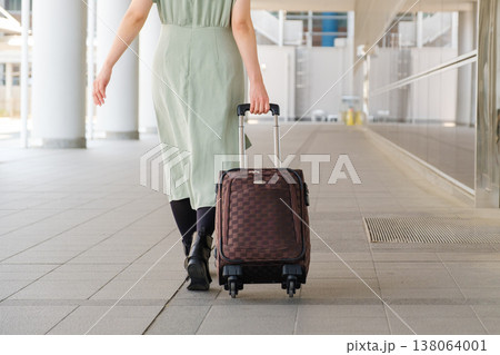 都心のコンコースを歩く旅行者の女性の後ろ姿：キャリーケースと都会の移動風景 138064001