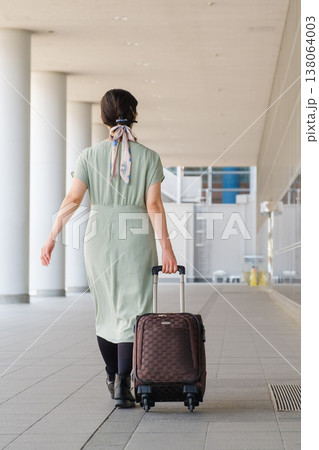 都心のコンコースを歩く旅行者の女性の後ろ姿：キャリーケースと都会の移動風景 138064003