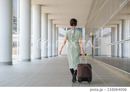 都心のコンコースを歩く旅行者の女性の後ろ姿：キャリーケースと都会の移動風景 138064006