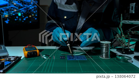 Computer Hardware Technician Repairing Motherboard with Soldering Iron in Electronics Lab. Computer Hardware Technician Repairing Motherboard with Soldering Iron in Electronics Lab. 138064072