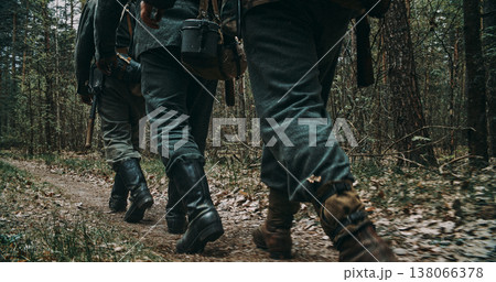 Rear view of German soldiers marching on forest path showing boots and gear Rear view of German soldiers marching on forest path showing boots and gear 138066378
