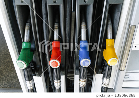 Fuel pump nozzles hanging at a modern gas station during a period of high oil prices. A conceptual photography showcasing the global energy crisis, increasing gasoline costs Fuel pump nozzles hanging at a modern gas station during a period of high oil prices. A conceptual photography showcasing the global energy crisis, increasing gasoline costs 138066869