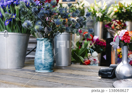 Cozy and authentic rustic flower shop counter with dried lavender and vintage gardening tools. An intimate workshop scene showing a hand tying a flower bouquet on a weathered wooden table with antique 138068627