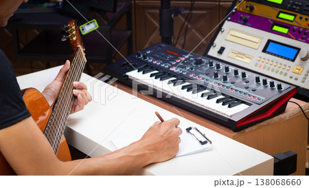 male musician writing a hit song by acoustic guitar in home studio 138068660
