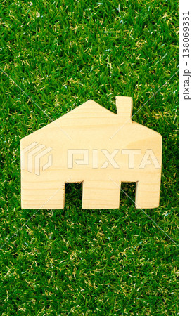 Wooden house shape placed on green grass surface in a natural setting during daylight 138069331