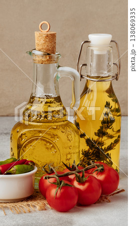 Olive oil and flavored oil with tomatoes and chili peppers on a table setting Olive oil and flavored oil with tomatoes and chili peppers on a table setting 138069335
