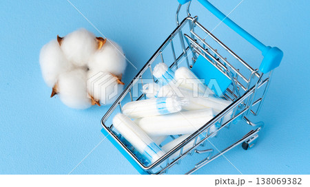 Shopping cart with cotton and tampons on a blue background Shopping cart with cotton and tampons on a blue background 138069382