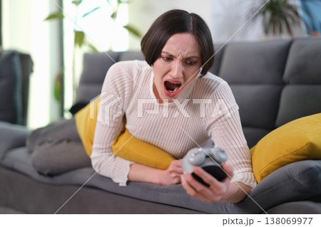 Excitement and frustration as a gamer battles through a challenging level in a cozy living room 138069977