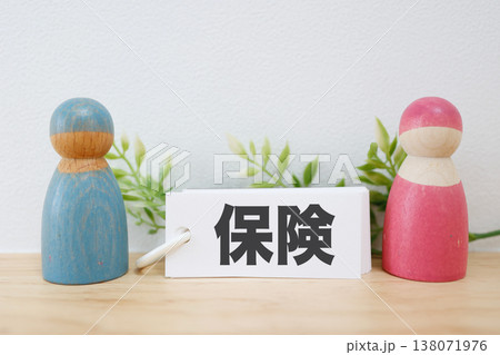 夫婦と保険を表す木製人形とカードのシンプル構図。 夫婦と保険を表す木製人形とカードのシンプル構図。 138071976