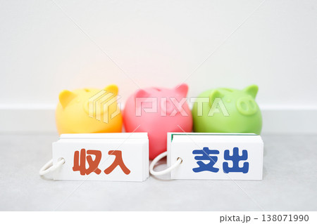 収入と支出を比較する豚の貯金箱と家計管理イメージ。 収入と支出を比較する豚の貯金箱と家計管理イメージ。 138071990