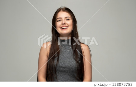 Young woman confidently smiling and laughing, expressing happiness and cheerful emotion while posing in a studio 138073782