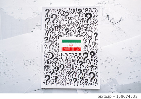 Iran flag sticker placed on paper covered question marks over blurred geographic maps. energy security, oil price surge, Strait of Hormuz closure, global supply disruption, fuel rationing 138074335
