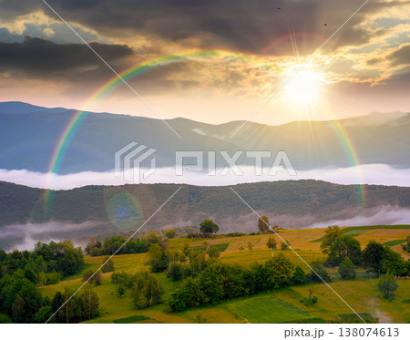 sunset over mountainous rural area during springtime. remote mountain landscape with forested rolling hills. wonderful foggy place of alpine countryside wallpaper. weather with rainbow sunset over mountainous rural area during springtime. remote mountain landscape with forested rolling hills. wonderful foggy place of alpine countryside wallpaper. weather with rainbow 138074613