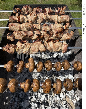 Close-up from above showing fresh meat being grilled on metal skewers. Close-up from above showing fresh meat being grilled on metal skewers. 138074637