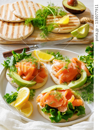 open-faced grilled pita sandwiches with lettuce, smoked salmon slices, avocado, dill, and lemon wedges open-faced grilled pita sandwiches with lettuce, smoked salmon slices, avocado, dill, and lemon wedges 138077911