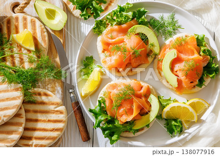 open-faced grilled pita sandwiches with lettuce, smoked salmon slices, avocado, dill, and lemon wedges open-faced grilled pita sandwiches with lettuce, smoked salmon slices, avocado, dill, and lemon wedges 138077916