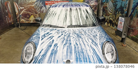 Blue car covered in soap foam at automatic car wash station 138078046