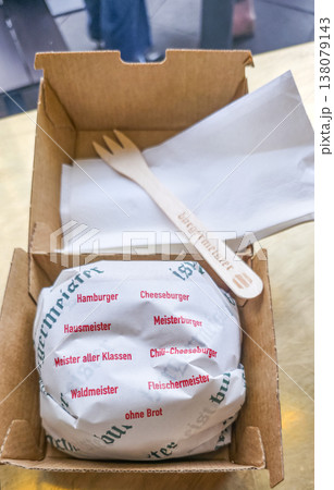 Gourmet burger wrapped in paper inside a takeout box with utensils Gourmet burger wrapped in paper inside a takeout box with utensils 138079143