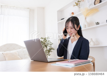 パソコンを見ながら困った顔をする20代女性 138080464