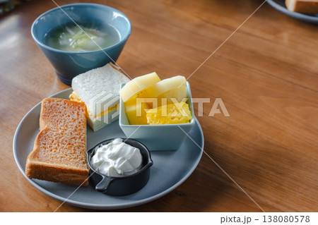 木のテーブルの朝食セット トーストとたまごサンドとフルーツ小鉢とヨーグルトとスープ 138080578