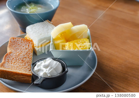 木のテーブルに置いた朝食プレート トーストとたまごサンドとフルーツとヨーグルトとスープ 木のテーブルに置いた朝食プレート トーストとたまごサンドとフルーツとヨーグルトとスープ 138080580