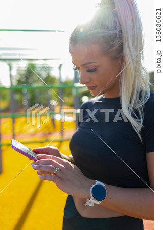 Woman using smartwatch and phone outdoors at workout station under sunlight Woman using smartwatch and phone outdoors at workout station under sunlight 138080621