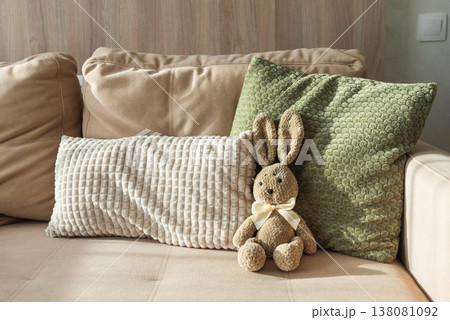 Plush Bunny sitting on sofa. Cozy Easter Decoration Plush Bunny sitting on sofa. Cozy Easter Decoration 138081092