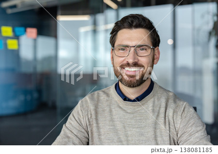 Smiling businessman wearing casual sweater and modern glasses posing for a portrait in a contemporary office, representing corporate success, confidence, and professionalism Smiling businessman wearing casual sweater and modern glasses posing for a portrait in a contemporary office, representing corporate success, confidence, and professionalism 138081185