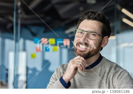 Successful bearded business man wearing glasses and a sweater, smiling and looking at the camera, showing confidence and innovative ideas in a modern office environment Successful bearded business man wearing glasses and a sweater, smiling and looking at the camera, showing confidence and innovative ideas in a modern office environment 138081186