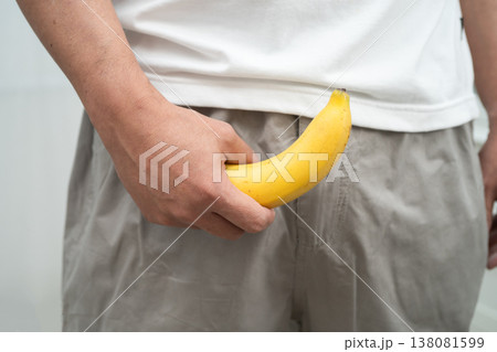 Male stands holding a banana, penis health. Male stands holding a banana, penis health. 138081599