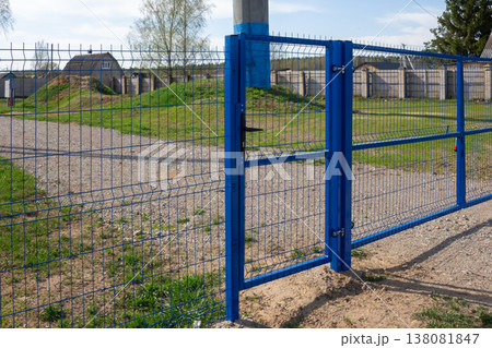 Secure blue welded mesh fencing with closed gate, red padlock visible, industrial or residential boundary Secure blue welded mesh fencing with closed gate, red padlock visible, industrial or residential boundary 138081847