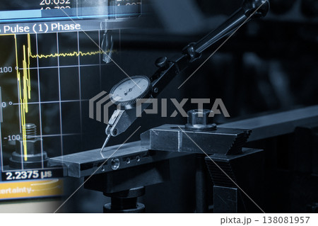Abstract industrial scene of a dial gauge setup for workpiece leveling integrated with a digital data graph display in a blue-toned tech environment. Abstract industrial scene of a dial gauge setup for workpiece leveling integrated with a digital data graph display in a blue-toned tech environment. 138081957
