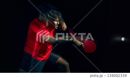 Table tennis player reacting to fast ball with motion blur in dark studio. 138082339
