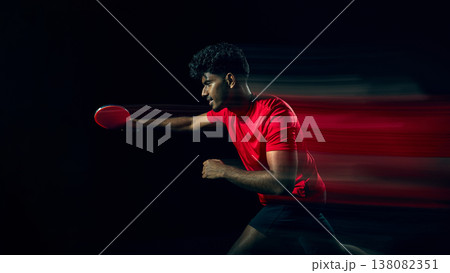 Table tennis player swinging racket with motion blur in dark studio. Table tennis player swinging racket with motion blur in dark studio. 138082351